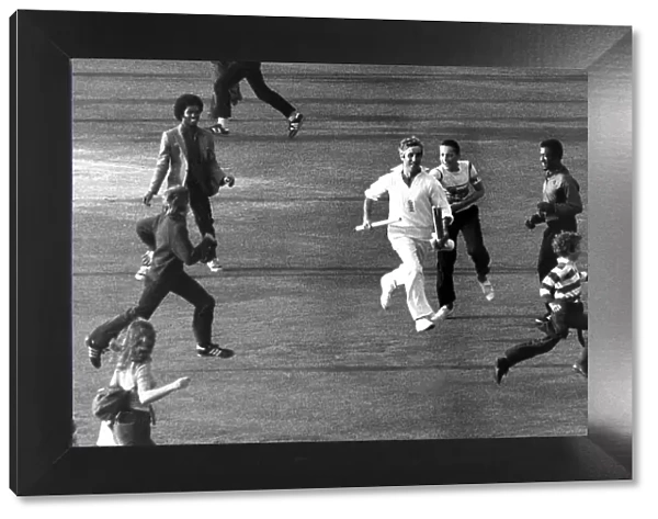 Mike Brearley runs off the pitch holding the cricket stumps