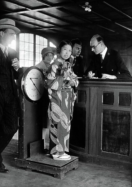 Miki, the Japanese artiste, standing with her dog on the scales at Le Bourget Airport, Paris 1928