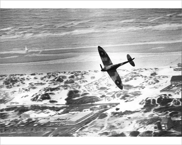 An RAF Spitfire flies over the dunes of Dunkirk