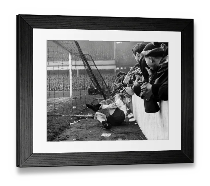 Framed Print : Spur's Terry Dyson lies in agony after colliding with the concrete wall at Upton Park after a challenge by a West Ham Player 1964