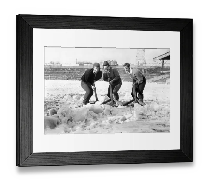 Framed Print : Bolton Wanderers players clear the snow from the pitch at Burnden Park