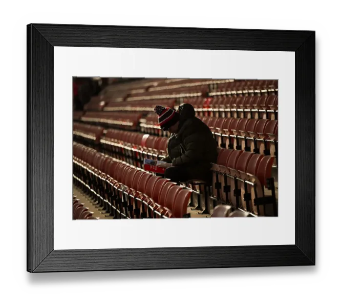 Framed Print : Welcome to Wrexham AFC - an early fan sitting reading the clubs programme hours before the game