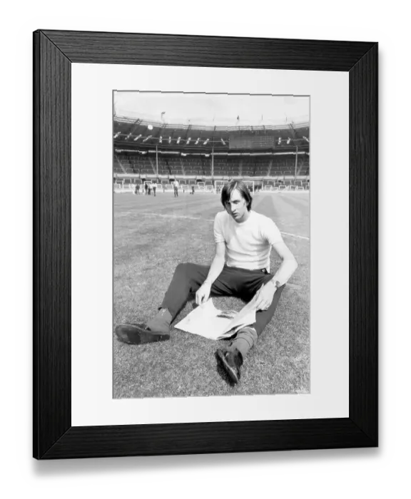Framed Print : Ajax's leading goalscorer Johan Cryuff's relaxes whilst reading a magazine on the famous Wembley pitch 1971