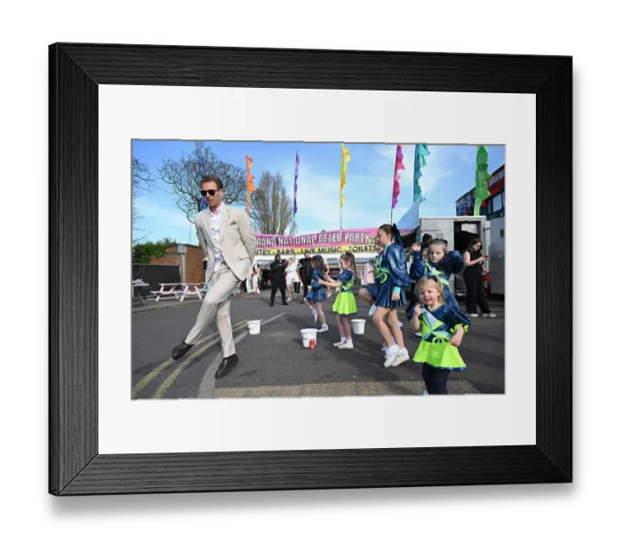 Framed Print : 2025 Grand National Aintree a race goer dances with children outside Aintree after racing on the Friday Framed Print : 2025 Grand National Aintree a race goer dances with children outside Aintree after racing on the Friday