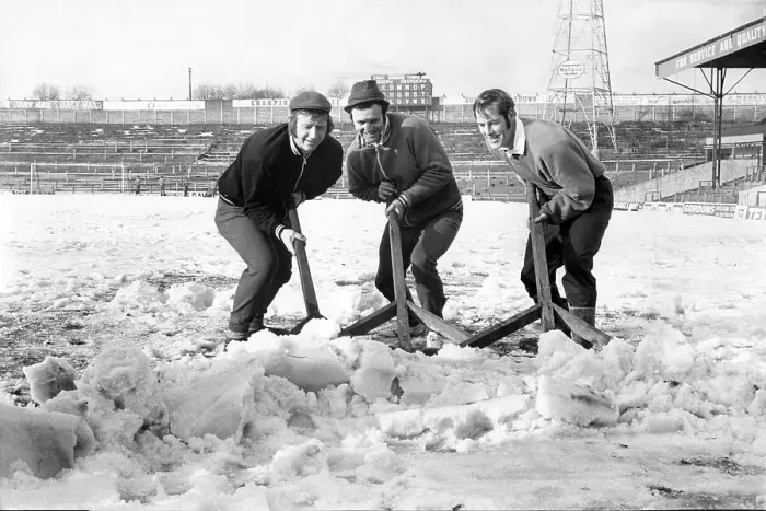 Framed Print : Bolton Wanderers players clear the snow from the pitch at Burnden Park