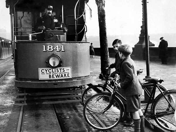 Children on bicycles crossing in front of a tram