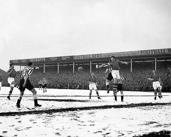 Geoff Thomas jumps high to head clear from Newcastle's centre forward Len White on a snow covered City Ground 1955