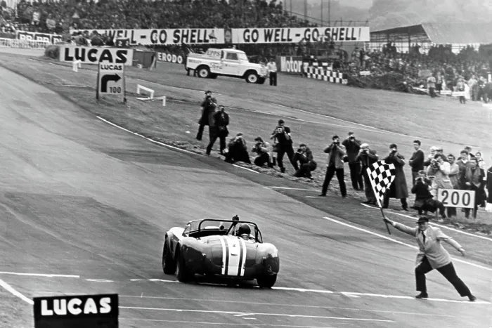 Framed Print : Jack Sears in his AC Cobra at Brands Hatch taking the winners flag 1964 Framed Print : Jack Sears in his AC Cobra at Brands Hatch taking the winners flag 1964