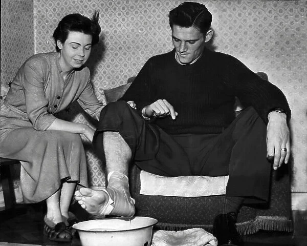 Manchester City footballer Bill Leivers soaking his injured foot in a bowl of water prepared by his wife, Shirley