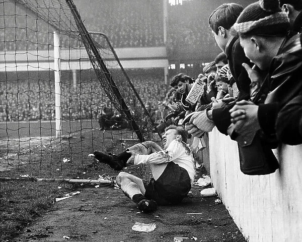 Spur's Terry Dyson lies in agony after colliding with the concrete wall at Upton Park after a challenge by a West Ham Player 1964