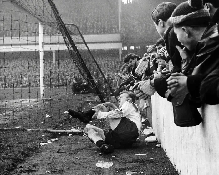 Framed Print : Spur's Terry Dyson lies in agony after colliding with the concrete wall at Upton Park after a challenge by a West Ham Player 1964