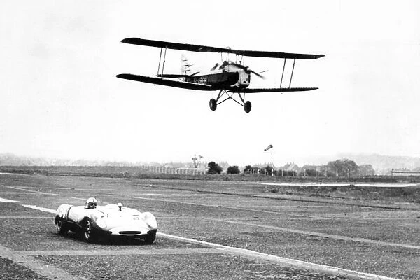 A Tiger Moth aircraft and a Lotus Ford 23B, racing at Usworth Aerodrome 1963