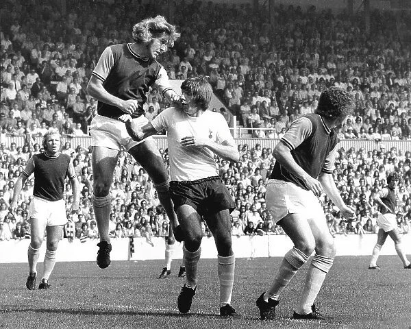 West Ham's Bobby Moore watches his team mate Tommy Taylor head the ball away from Tottenham's Martin Peters