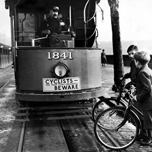 Children on bicycles crossing in front of a tram