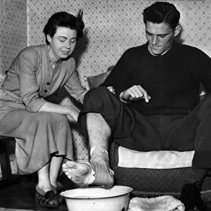 Manchester City footballer Bill Leivers soaking his injured foot in a bowl of water prepared by his wife, Shirley