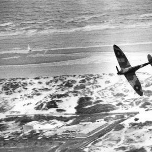 An RAF Spitfire flies over the dunes of Dunkirk