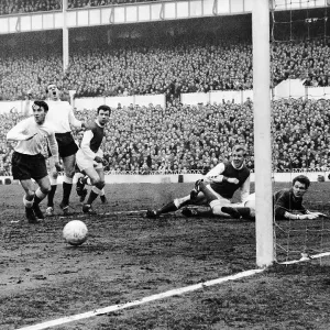 Spur's Laurie Brown watches his shot hit the post as Arsenal's keeper Jim McClelland and centre-half Ian Ure look on Spur's Laurie Brown watches his shot hit the post as Arsenal's keeper Jim McClelland and centre-half Ian Ure look on