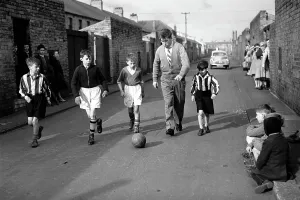 Fifties Prints: Bobby Charlton plays football with children in his home town of Ashington