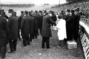 Spurs Prints: A police officer buys snacks from a vendor during the 1982 FA Cup quarter-final at Stamford Bridge